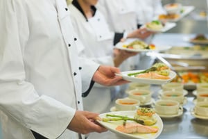 Chef holding salmon dishes standing in a row with colleagues-1