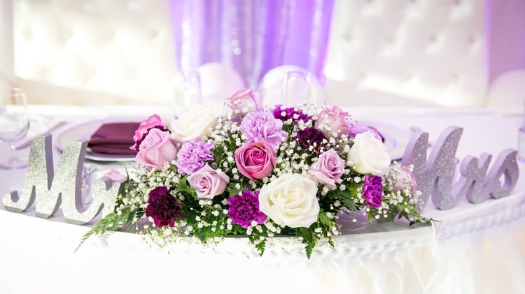 A beautiful arrangement of purple and white flowers adorned the sweetheart table