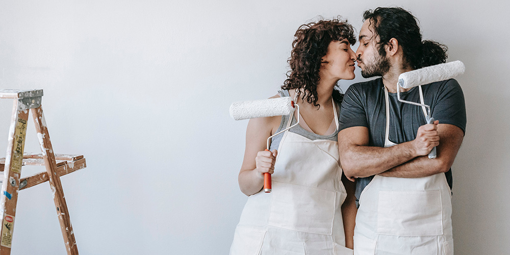 Couple kissing and holding paint rollers
