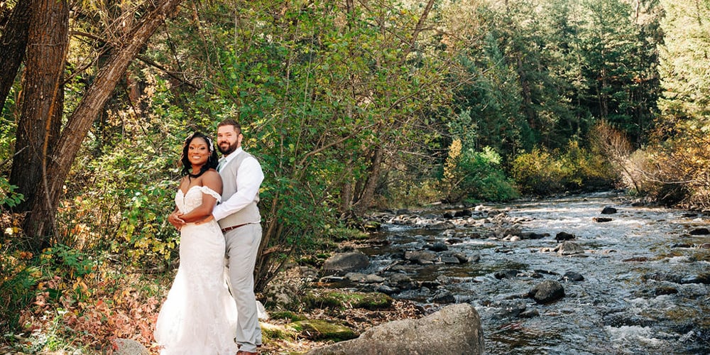 Newlyweds posing next to the creek at Boulder Creek by Wedgewood Weddings
