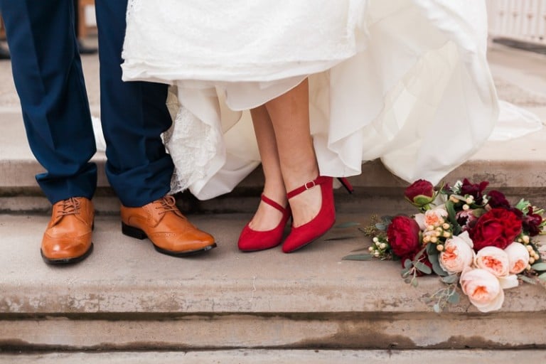 bride's red heels for wedding with bouquet and groom's shoes