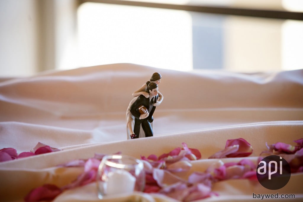 cake topper with groom holding a football for a sports wedding theme