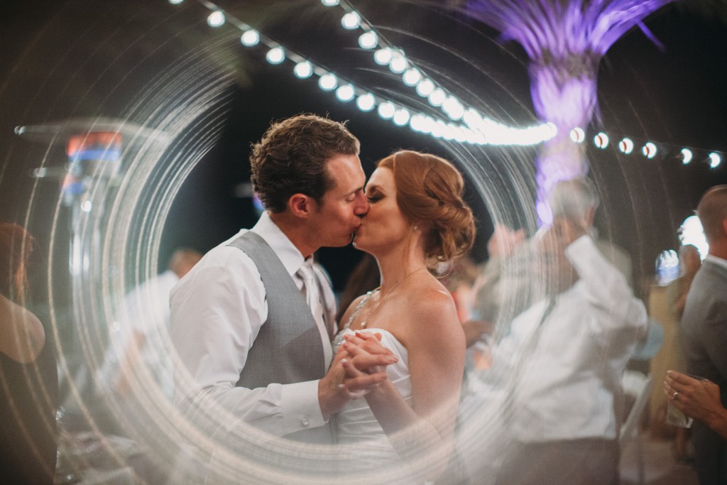 bride and groom kissing under hanging lights